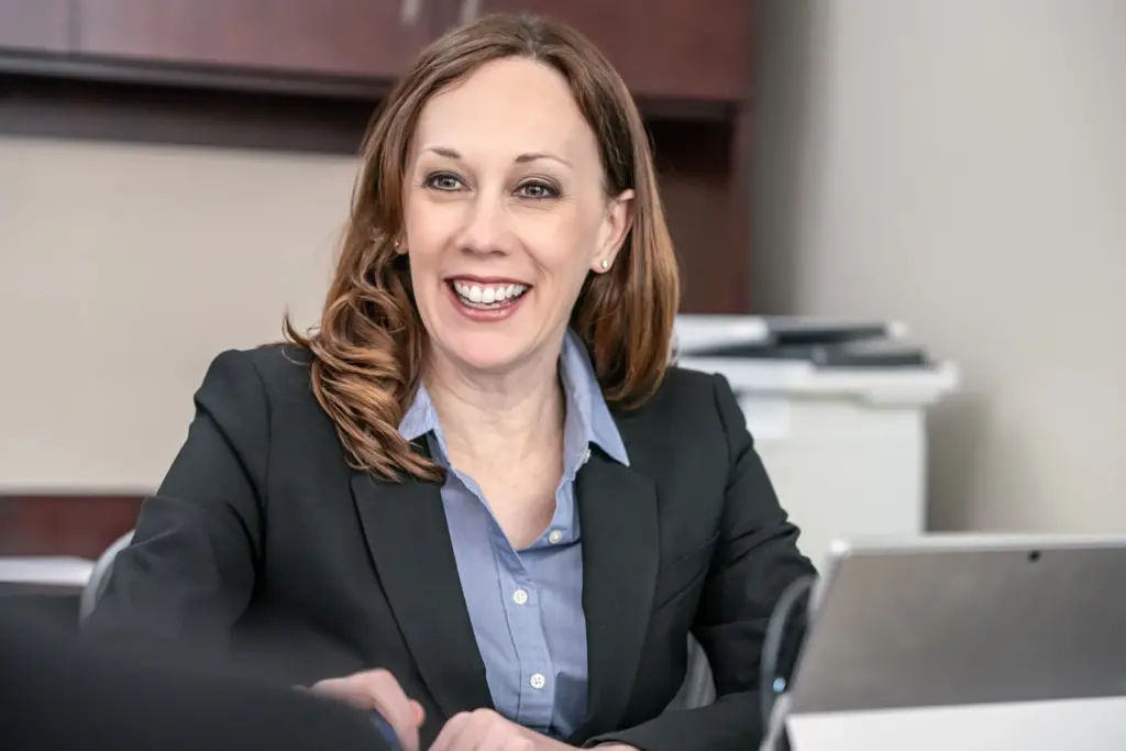 Sara sitting at her desk smiling and listening to a client.