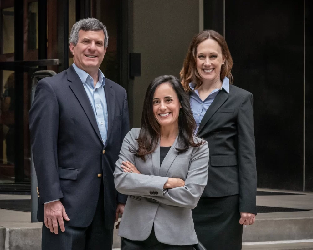 Three partners standing outside in front of their office.