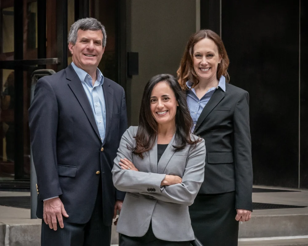 Three partners standing outside in front of their office.